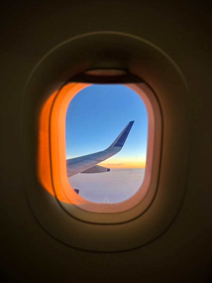 A stunning view of an airplane wing through a window at sunset, capturing the serene sky.